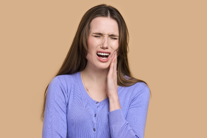 Woman during a dental emergency fighting severe tooth pain in Portage, MI